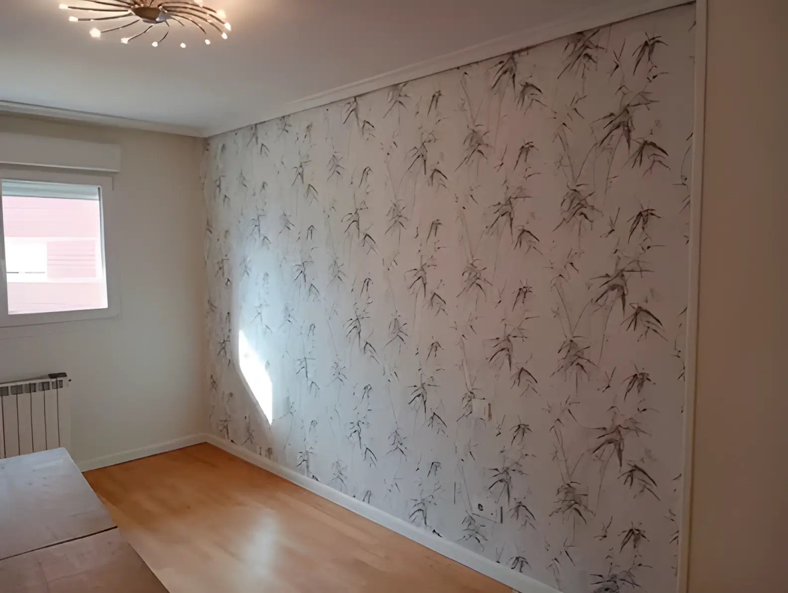 Los Pintores Valladolid colocando papel pintado en pared de acento de habitación luminosa