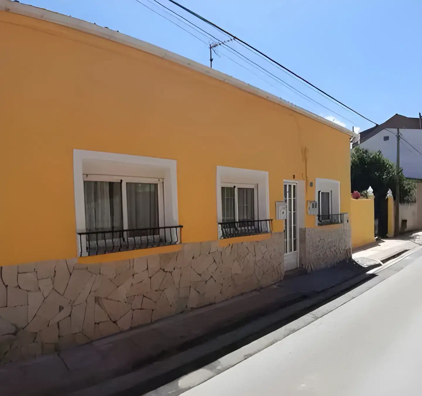 Los Pintores Valladolid Fachada de casa tradicional pintada en color amarillo con zócalo de piedra